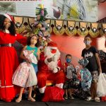 Simone Sampaio distribui presentes ao lado de Papai Noel de máscara na Dragões da Real Colunismo Social