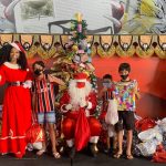 Simone Sampaio distribui presentes ao lado de Papai Noel de máscara na Dragões da Real Colunismo Social