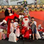 Simone Sampaio distribui presentes ao lado de Papai Noel de máscara na Dragões da Real Colunismo Social