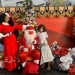 Simone Sampaio distribui presentes ao lado de Papai Noel de máscara na Dragões da Real Colunismo Social